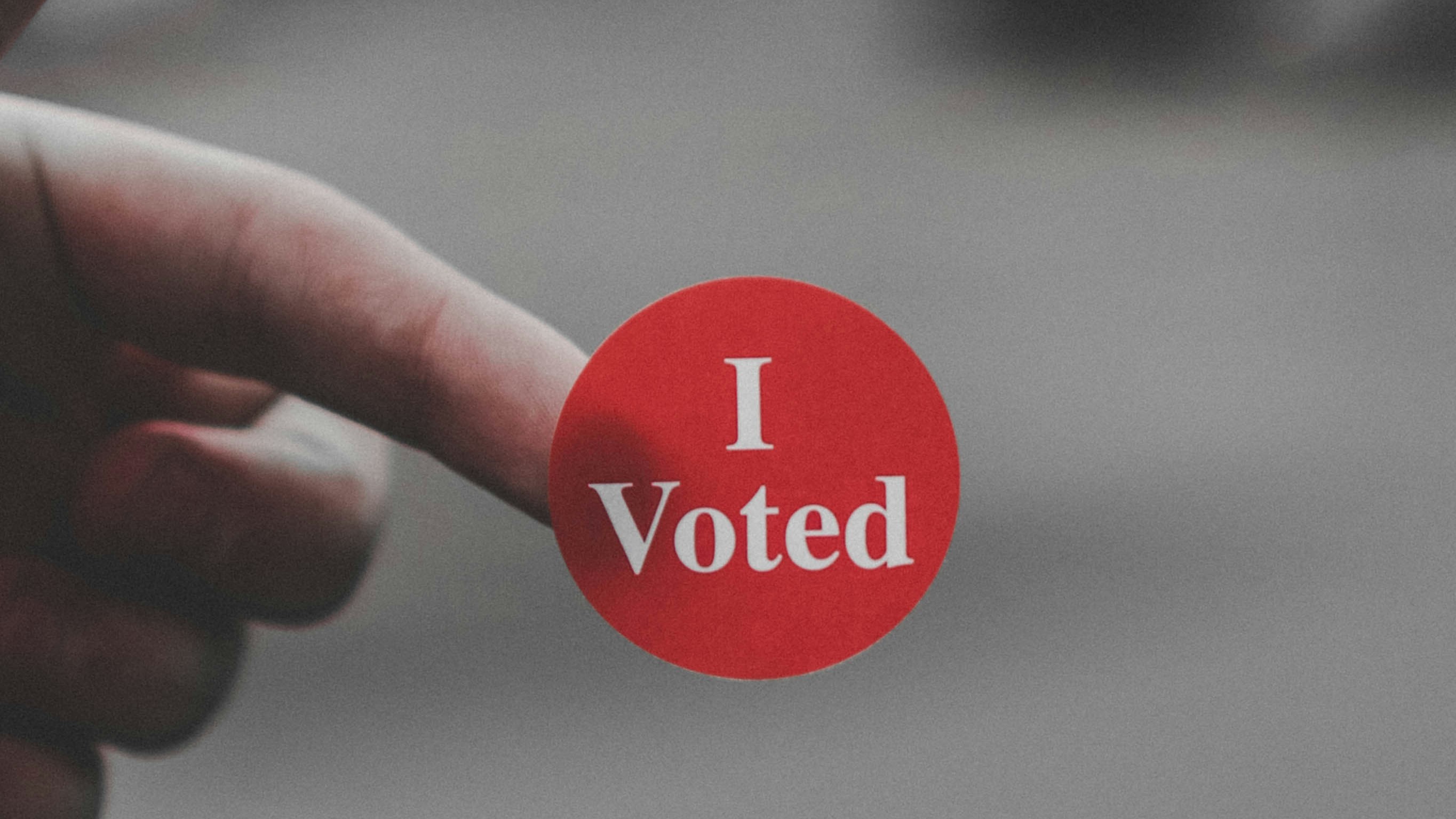 Hand holding an "I voted" sticker.