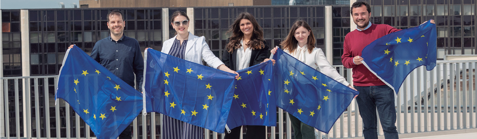 Young people smiling and holding EU flags.